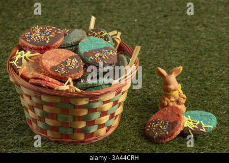 Colourful Easter biscuits in a woven basket in a meadow with a rabbit figure Stock Photo