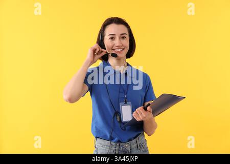 Technical support call center. Smiling operator with folder on yellow background Stock Photo