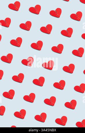 Red paper craft torn heart pattern on pastel blue background, vertical wallpaper. Creative Valentine's Day poster idea with broken heart Stock Photo