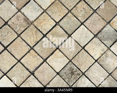 Natural stone marble tiles in diamond shape pattern. Outdoor honed tiles with random veins in yellow and beige color with black grouts.  wall or floor Stock Photo