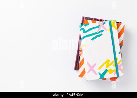 A stack of color notepads lies chaotically on a white minimal background. Back to school concept. Study, office, business concept, top view Stock Photo