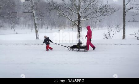 CHISINAU, MOLDOVA - JANUARY 29, 2021 Beautiful scene in the winter park with a mother and child enjoying a sleigh ride. Idyllic and peaceful scene wit Stock Photo