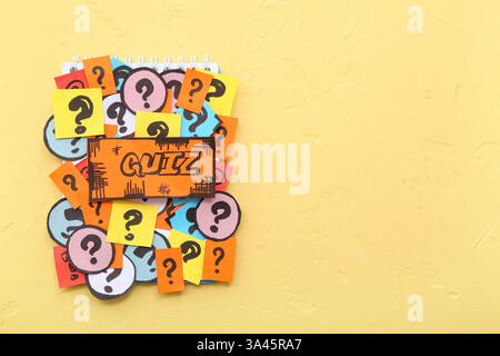 Notebook with quiz card and question marks on yellow background Stock Photo