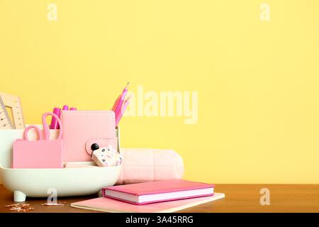 Holder with different stationery and notebooks on wooden desk Stock Photo