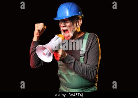 Mature miner man shouting into megaphone on black background Stock Photo