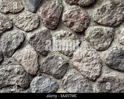 Natural random cut grey cobblestone cemented on a wall surface. Series of natural gravel or cobble stones exposed and weathered. Suitable for ancient Stock Photo