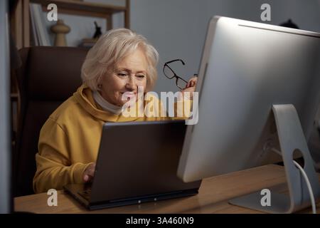 Focused elderly woman using desktop computer at home portrait shot Stock Photo
