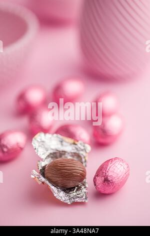 Chocolate easter eggs wrapped in pink colored foil on a pink background. Stock Photo