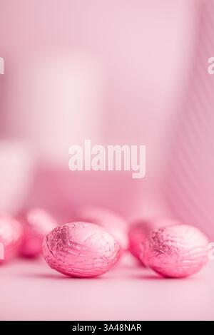 Chocolate easter eggs wrapped in pink colored foil on a pink background. Stock Photo