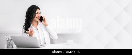 Smiling hispanic lady talking on the phone at office Stock Photo