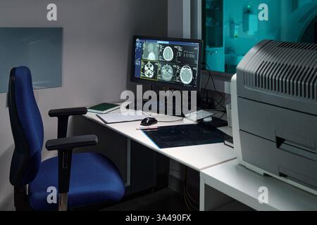 Office setting featuring high-tech equipment and multiple computer monitors displaying imaging data. Focus on organization and use of advanced technology tools and devices Stock Photo