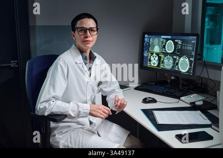 Portrait of scientist in laboratory holding glasses while analyzing data on computer screens from diagnostic tests, showcasing scientific research environment and modern technology Stock Photo