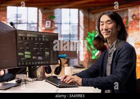 Portrait of happy CTO manager using PC in startup office to design and implementing algorithms enabling machine learning. Cheerful tech venture senior technician conducts code reviews to fix bugs Stock Photo