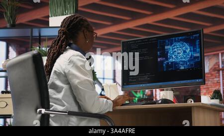 Teleworking programmer using computer for artificial intelligence computing through self learning algorithms. Remote worker working with AI deep neural networks on desktop PC, camera B Stock Photo