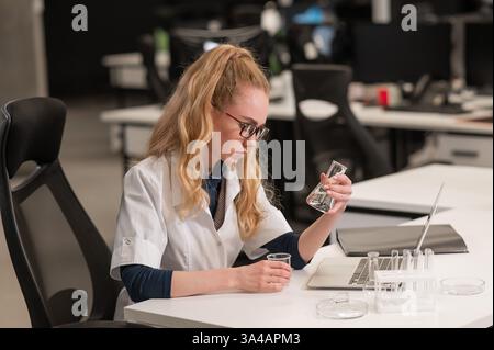 Caucasian woman in a medical gown doing laboratory experiments.  Stock Photo