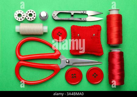 Different sewing supplies on green background, flat lay Stock Photo