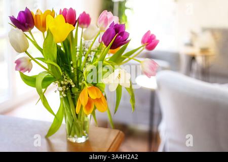Colorful bouquet of tulip flowers on a wooden table in the living room, cheerful spring and Easter decoration, copy space, selected focus, narrow dept Stock Photo