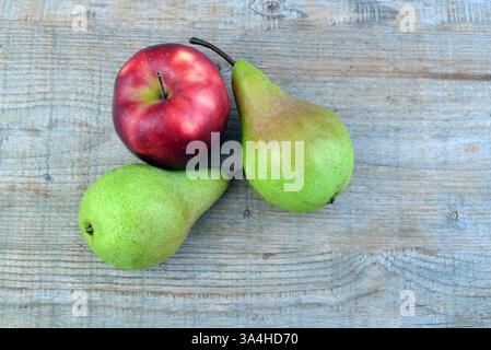 Red apple and two green pears on rustic wooden background. Stock Photo