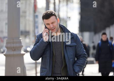 Young man talking on mobile phone on city street at spring Stock Photo