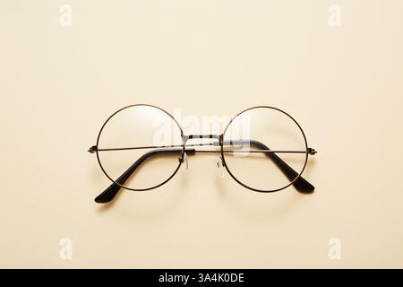 Glasses in round thin metal frame isolated on beige surface. Stock Photo