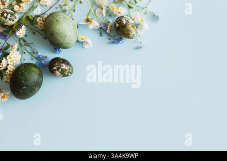Easter flat lay. Stylish easter eggs and spring flowers on blue background, space for text. Easter modern minimal banner. Season greetings mockup Stock Photo