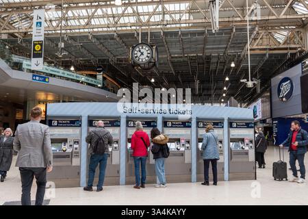 People or passengers buying rail tickets at self-service machines in Waterloo Railway Station, London, England, UK Stock Photo
