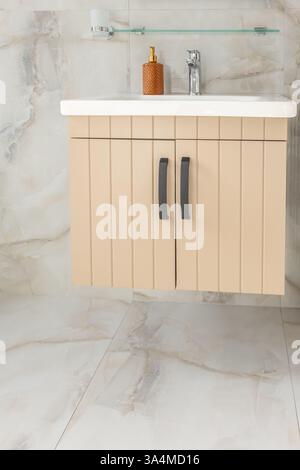 A bathroom with a wooden two doors cabinet. Bathroom furniture in the modern apartment. Tiled ceramic flooring. Wooden countertop bathroom. Nobody, cl Stock Photo