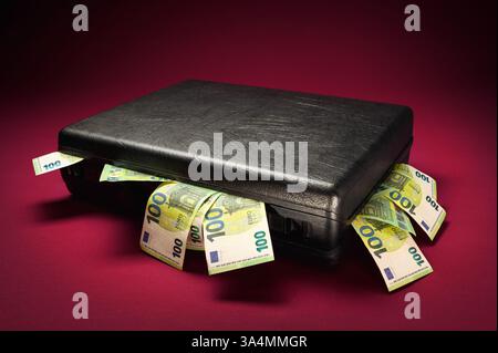A briefcase overflowing with euro banknotes. Concept studio shot on illuminated burgundy red background with dark vignette Stock Photo