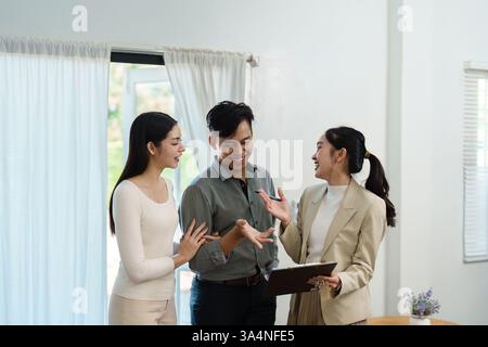 Real estate consultation. Engaging discussion between a real estate agent and two clients in a modern home setting. Stock Photo