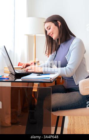 Concentrated caucasian woman working remotely on a laptop at home office Stock Photo