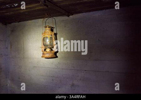 Old, rusty and dirty metal oil lamp hanging inside. Stock Photo