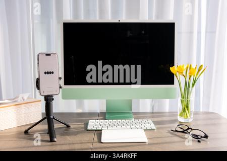 Prague, Czech republic - February 24, 2025: Work place with iMac and iPhone with open Chat Gpt application on screen. Work assistant with Open Ai Stock Photo