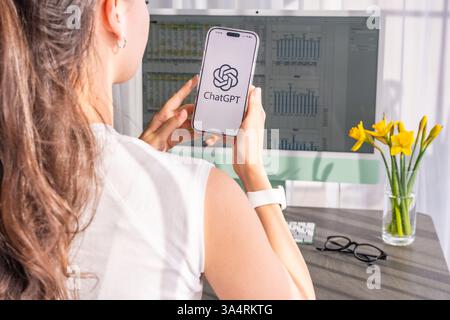 Prague, Czech republic - February 24, 2025: Young woman using a ChatGPT app on her smartphone while working at home. AI-powered assistants enhance Stock Photo