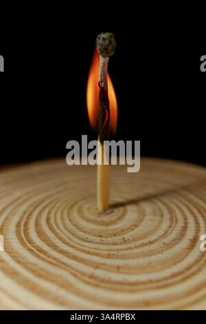 Burning match on wooden disk isolated on black background with copy space Stock Photo