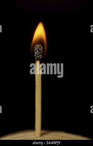Close-up of a burning match on a wooden disk isolated on black background with copy space Stock Photo