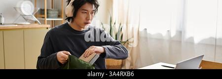 Focused young man prepares for online studies while seated at his home workspace, banner Stock Photo