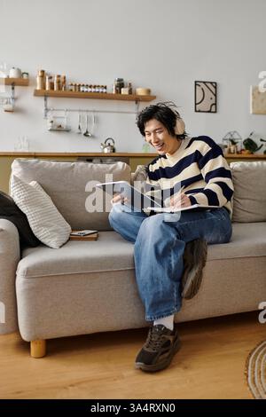 A handsome young student studies diligently at home, using his laptop and taking notes. Stock Photo