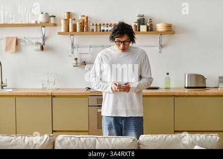 Young handsome man relaxes in his stylish apartment while using his mobile phone. Stock Photo