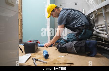 Man assembling plumbing pipes in the bathroom. Stock Photo