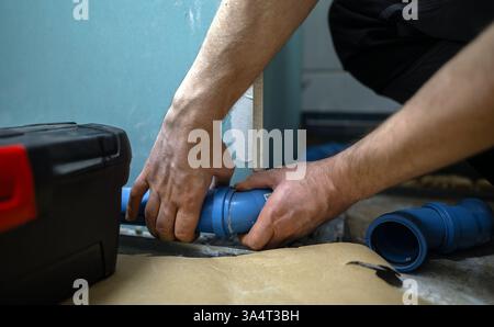 Man assembling plumbing pipes in the bathroom. Stock Photo