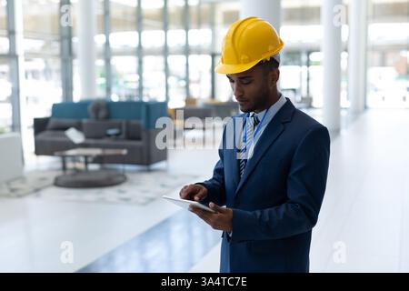 Engineer in suit using tablet in modern office building, focused on work, copy space Stock Photo