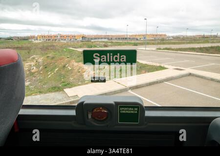 A sign in Spanish that says "Salida" (Exit) and a device with a sign that says "apertura de emergencia" (Emergency Exit) on the window of a passenger Stock Photo