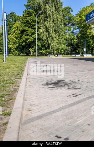 Liepaja , Latvia- July 7, 2023: Stains on the road parking bays from the car oil. Black oil stains on the asphalt. Stock Photo