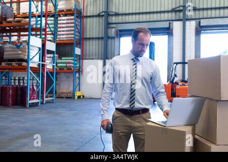 Managing inventory in warehouse, businessman using laptop and barcode scanner efficiently, copy spac Stock Photo