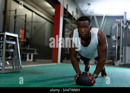 Athletic man doing plank exercise with medicine ball in modern gym, copy space Stock Photo