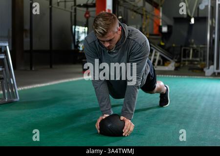 Athletic man doing plank exercise on medicine ball in gym, focused on strength Stock Photo