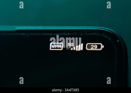 Close-up of a smartphone screen displaying VPN, 5G network, and battery status icons. Cybersecurity, internet privacy, and mobile technology concept. Stock Photo