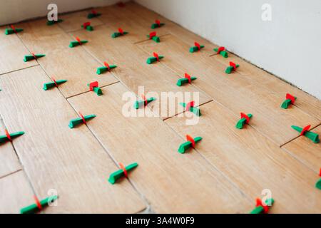 Tile leveling system with plastic clips and wedges. Wood effect narrow tiles installed on floor. Renovation of home Stock Photo