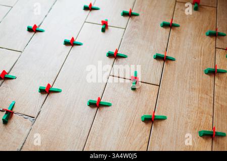 Tile leveling system with plastic clips and wedges. Wood effect narrow tiles installed on floor. Renovation of home Stock Photo