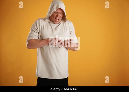 Angry, mad, showing something on the palm of the hand. Man is against background in the studio. Stock Photo